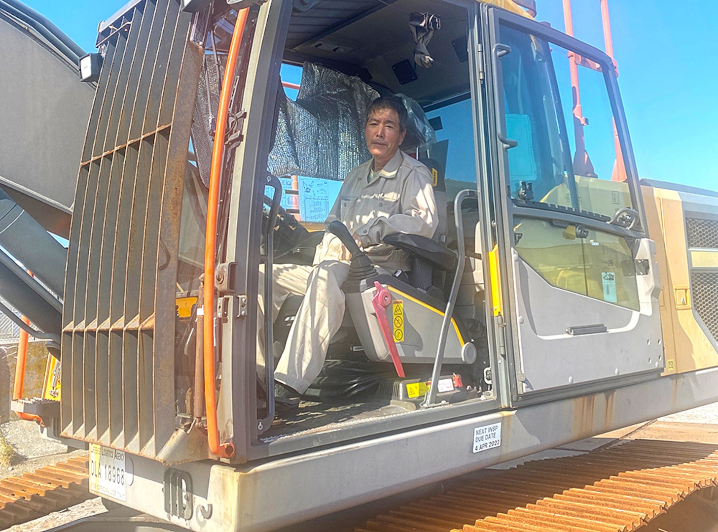 A man poses in the driver seat of a large tractor.