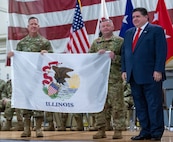 Illinois Gov. JB Pritzker, right, and Maj. Gen. Rodney Boyd, the Adjutant General of Illinois and Commander of the Illinois National Guard, presents Lt. Col. Jason Celletti, commander, 1st Assault Helicopter Battalion, 106th Aviation Regiment, with an Illinois state flag during the mobilization ceremony Feb. 7 at the 182nd Airlift Wing, Peoria. The flag will travel with the unit as they deploy to the U.S. Central Command area of responsibility.