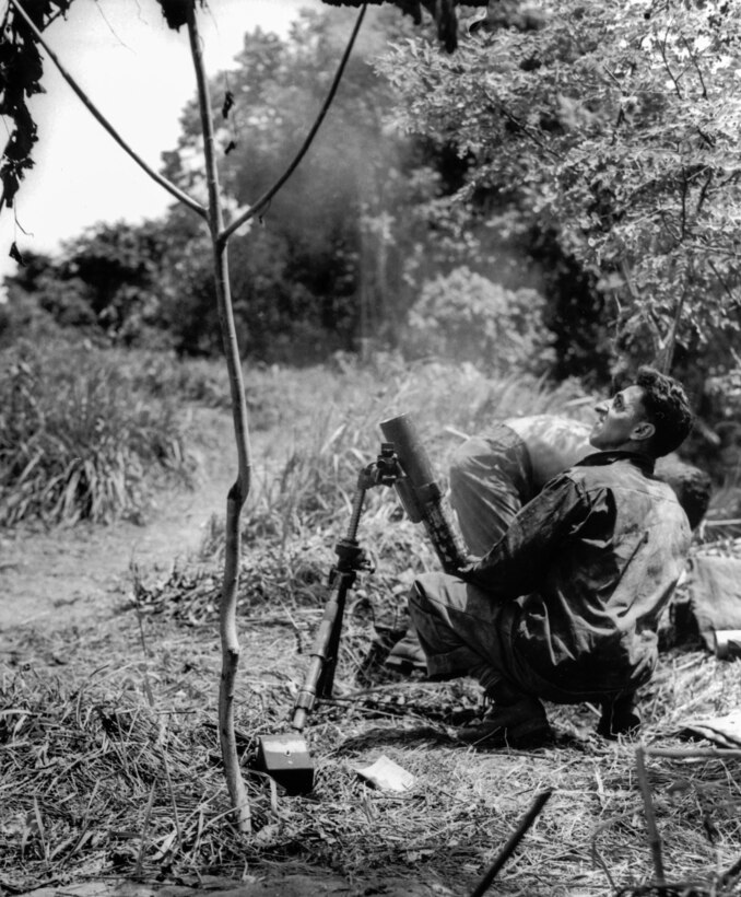 Soldier firing an M2 60mm mortar into the enemy lines at Buna Mission, December 1942.