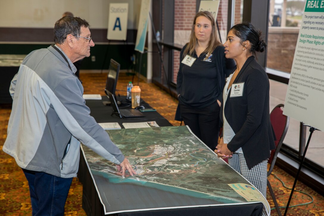 two people talking to one person while referencing a large map on a table