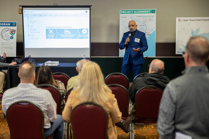 one person standing in front of a seated crowd talking into a microphone
