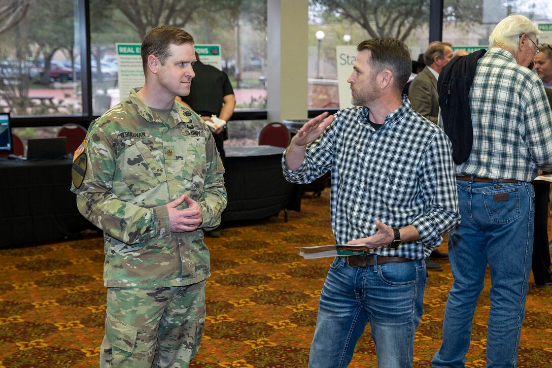 one person in a military uniform talking to another person in civilian clothes