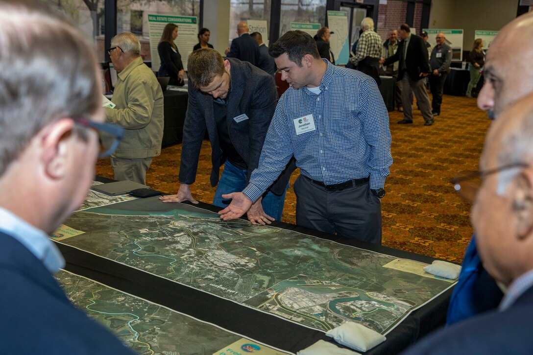 one person talking to another while referencing a large map on a table