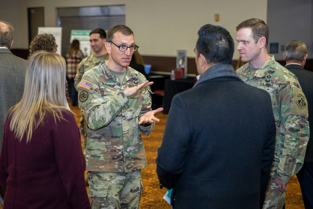 One uniformed person talking with one uniformed person and two civilians