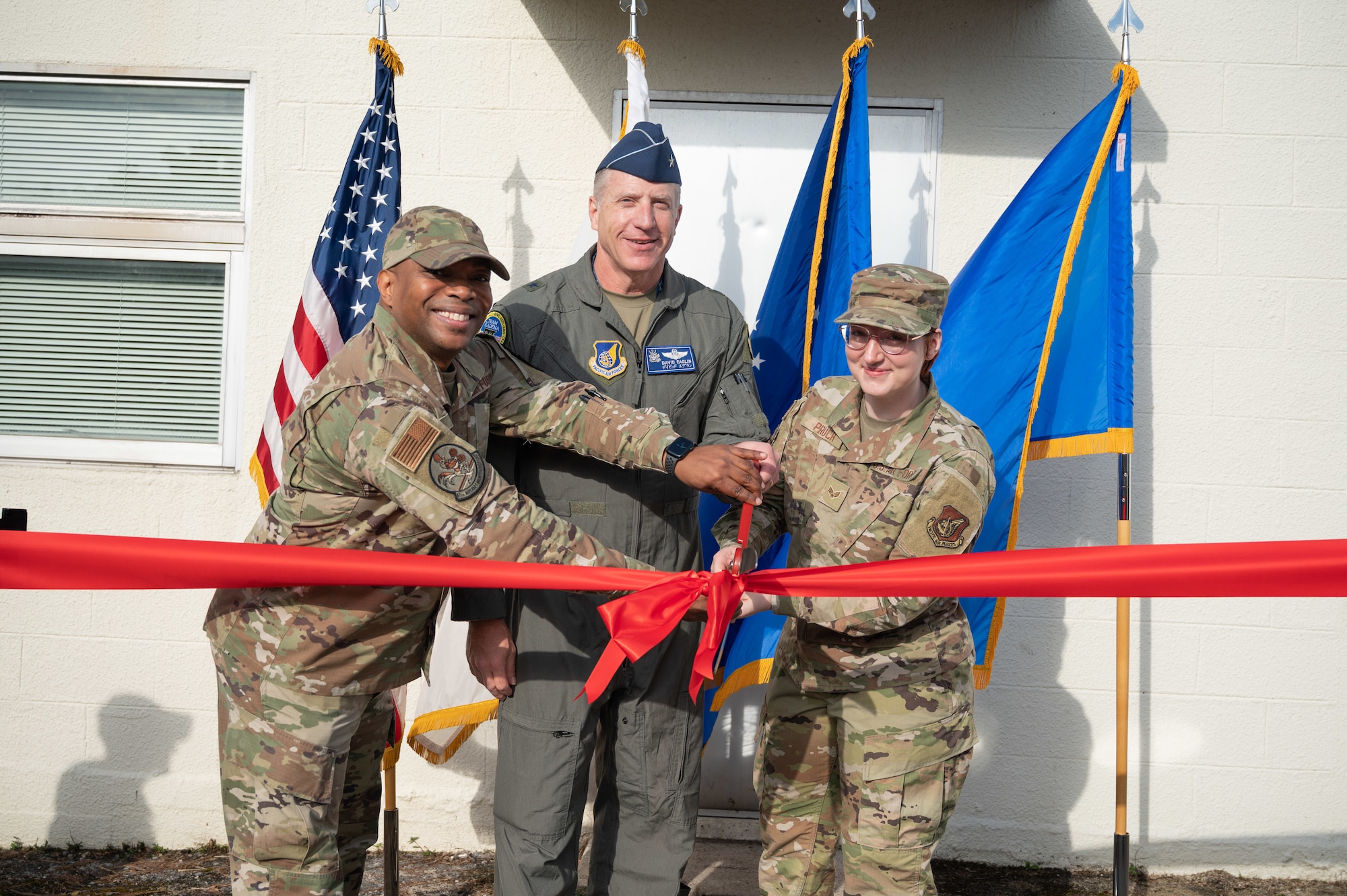 Airmen cut a ribbon with scissors