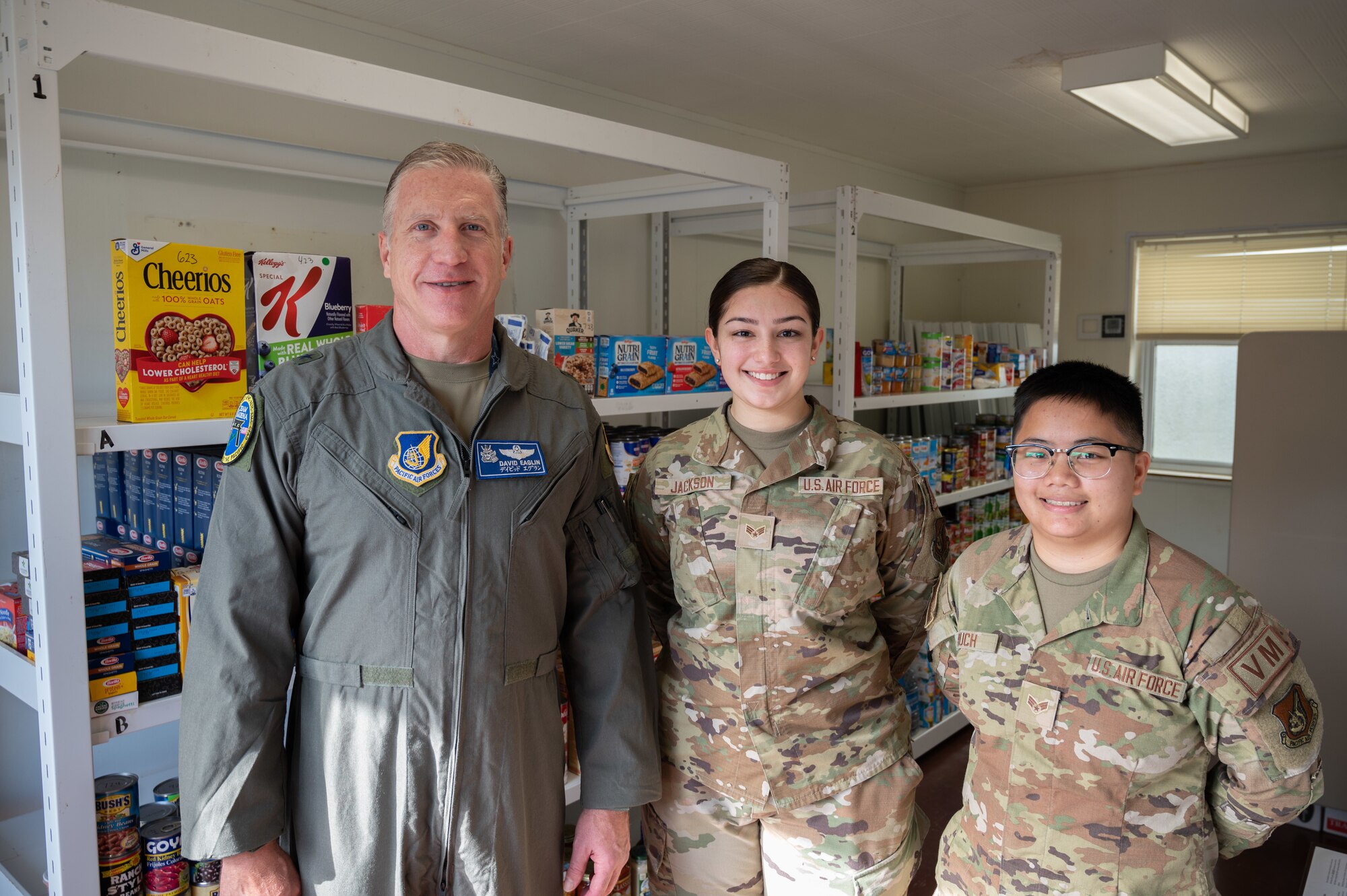 Airmen pose for a photo in front of shelves of food