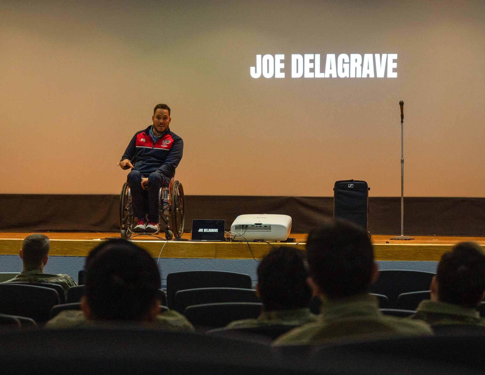 A man in a wheelchair speaks from a raised stage
