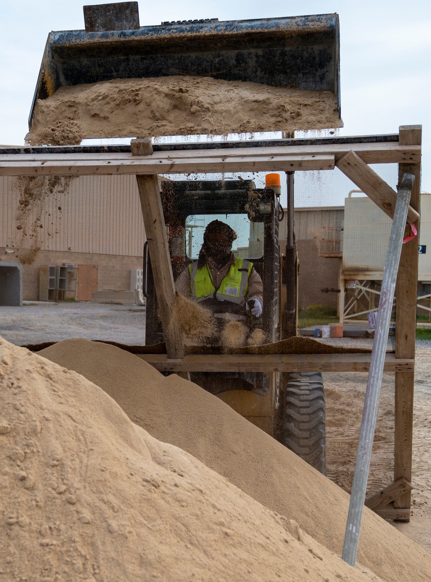 Muntaz Akbar, Prime One contractor, pours sand over a sieve to filter out large particulates at Ali Al Salem Air Base, Kuwait, Feb. 7, 2023.