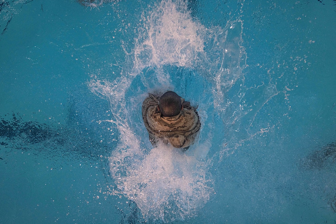 A Marine Corps recruit splashes into the water as seen from above.