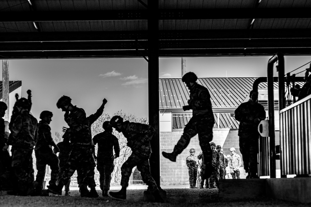 Paratroopers jump from a  low step.