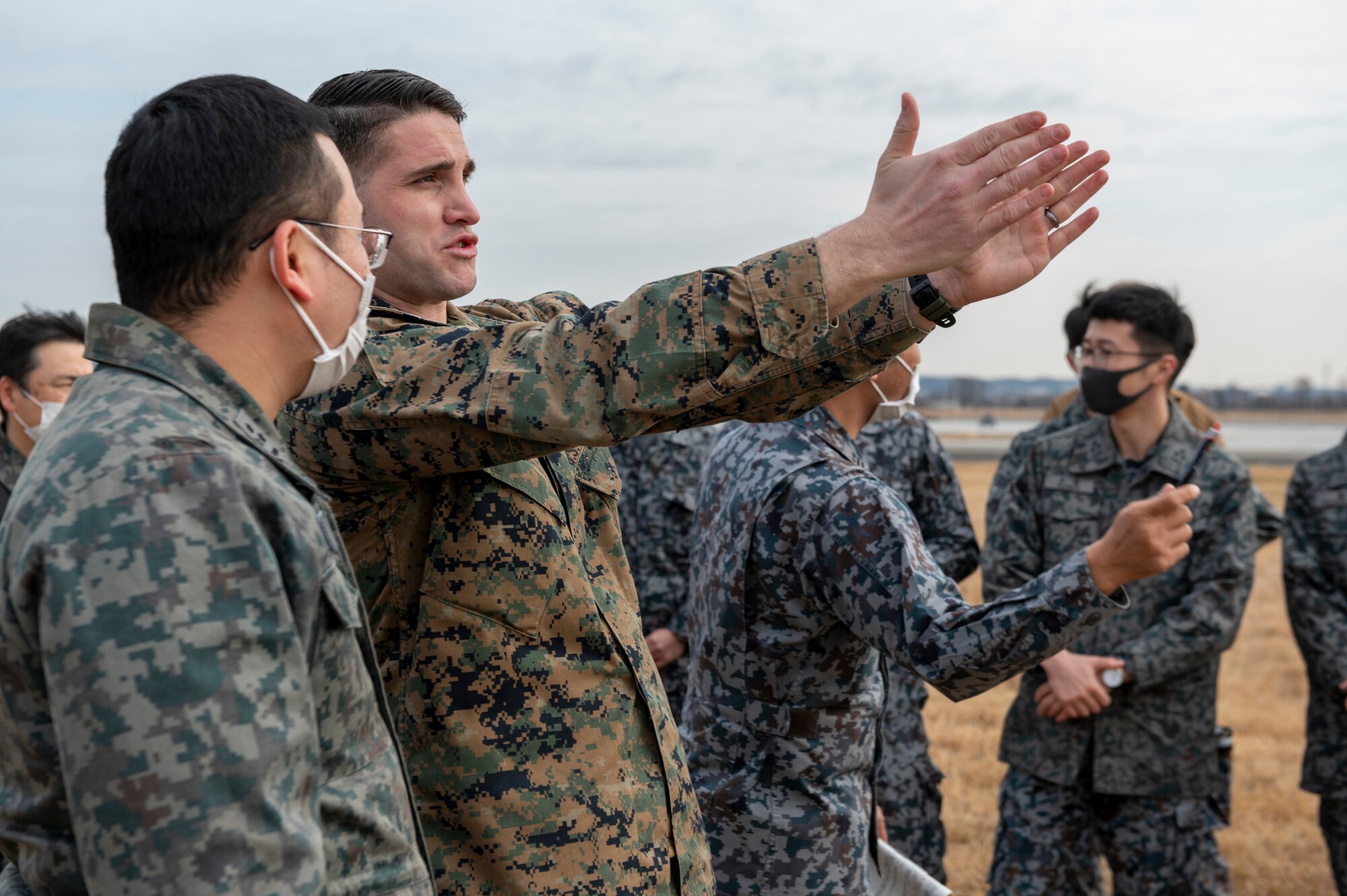 A U.S. marine gestures with both arms in front of him to a Japanese air force member