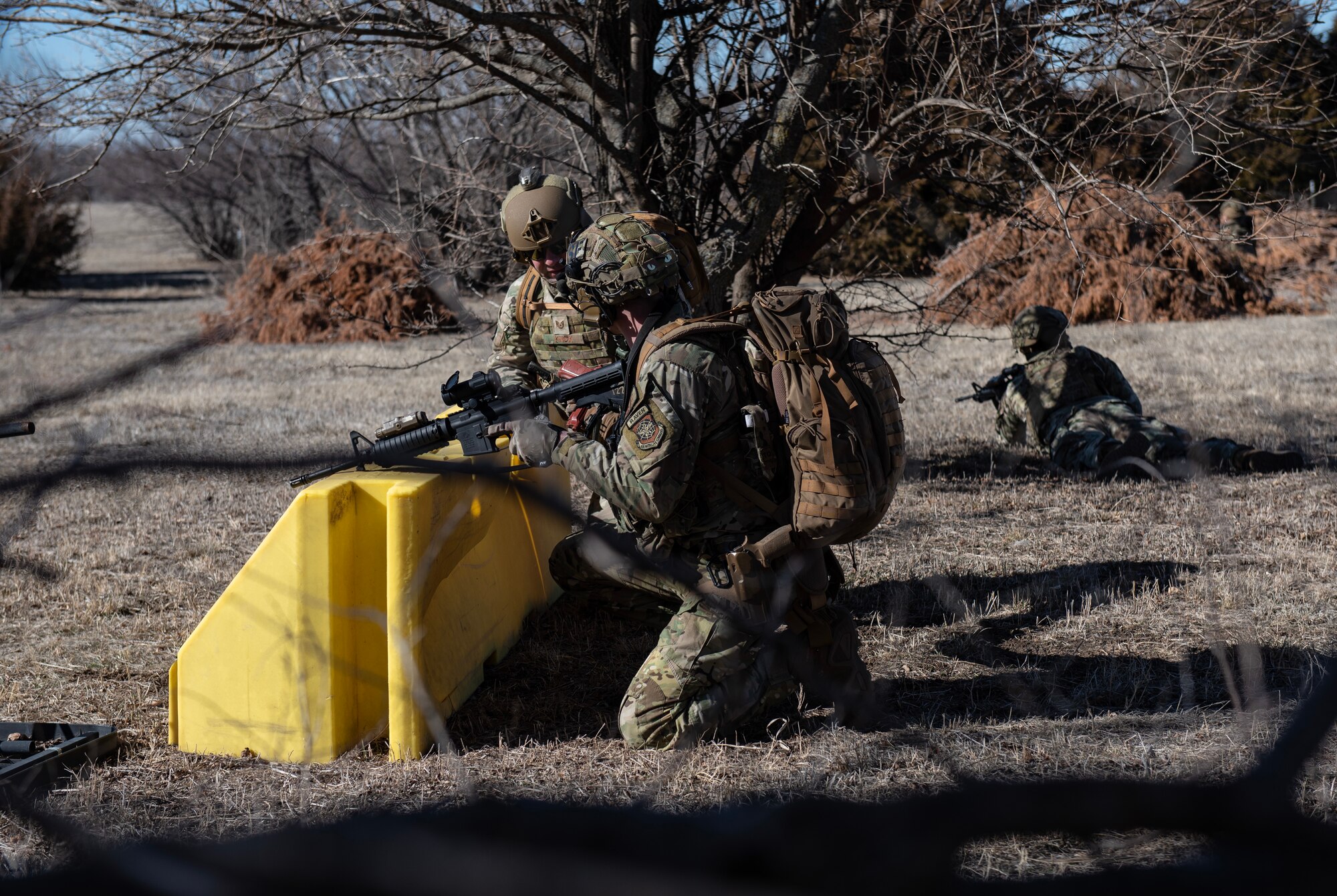Senior Airman Matthew D’Ambrosia, front, 22nd Security Forces Squadron patrolman, provides a situation report for clearing buildings to Tech. Sgt. Joseph Knox, middle, 22nd SFS flight sergeant, during joint training at McConnell Air Force Base, Kansas, Feb. 3, 2023. Along with the clearing buildings, the Airmen trained with U.S. Army Soldiers from the 3rd Assault Helicopter Battalion, 1st Aviation Regiment from Fort Riley, Kansas, to practice tactical takeoffs and landings in a UH-60 Blackhawk. (U.S. Air Force photo by Staff Sgt. Tryphena Mayhugh)