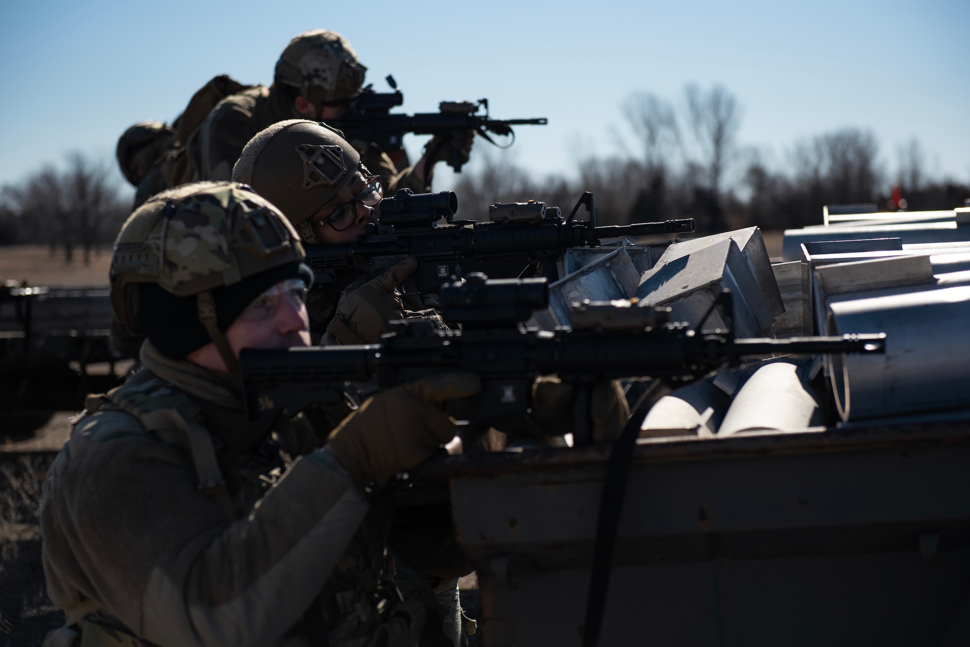 Staff Sgt. Daniel McGinnis, front, 22nd Security Forces Squadron patrolman, Senior Airman Alexis Williams, middle, 22nd SFS flight leader, and other defenders kneel behind a barricade during joint training at McConnell Air Force Base, Kansas, Feb. 3, 2023. Along with tactical approaches and retreats to clear buildings, the Airmen trained with U.S. Army Soldiers from the 3rd Assault Helicopter Battalion, 1st Aviation Regiment from Fort Riley, Kansas, to practice tactical takeoffs and landings in a UH-60 Blackhawk.  (U.S. Air Force photo by Staff Sgt. Tryphena Mayhugh)