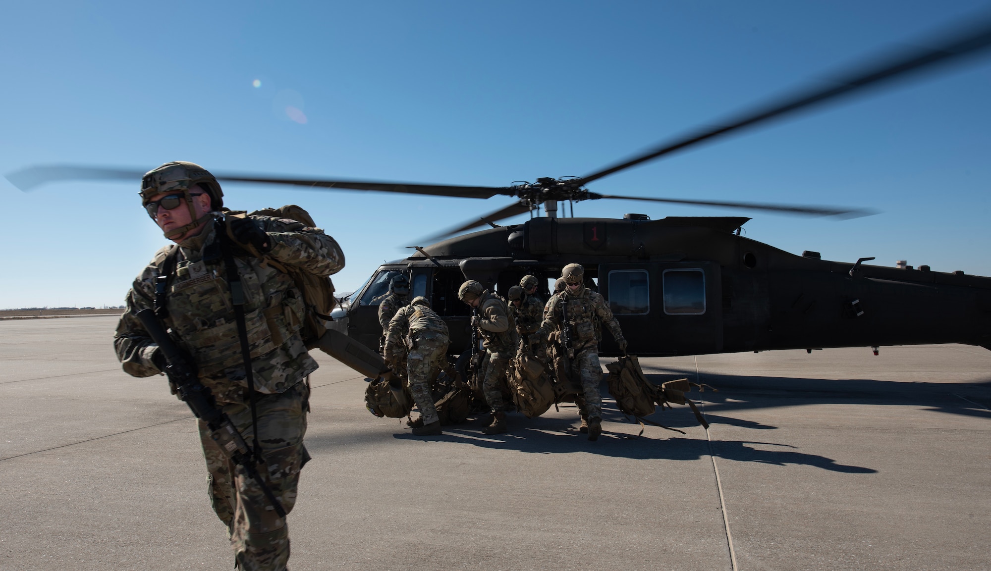 Tech. Sgt. Bradley Hornberger, 22nd Security Forces Squadron combat arms training and maintenance instructor, and other defenders disembark from a U.S. Army UH-60 Blackhawk during joint training at McConnell Air Force Base, Kansas, Feb. 3, 2023. The Airmen trained with U.S. Army Soldiers from the 3rd Assault Helicopter Battalion, 1st Aviation Regiment from Fort Riley, Kansas, to practice tactical takeoffs and landings in the Blackhawk during the training. (U.S. Air Force photo by Staff Sgt. Tryphena Mayhugh)