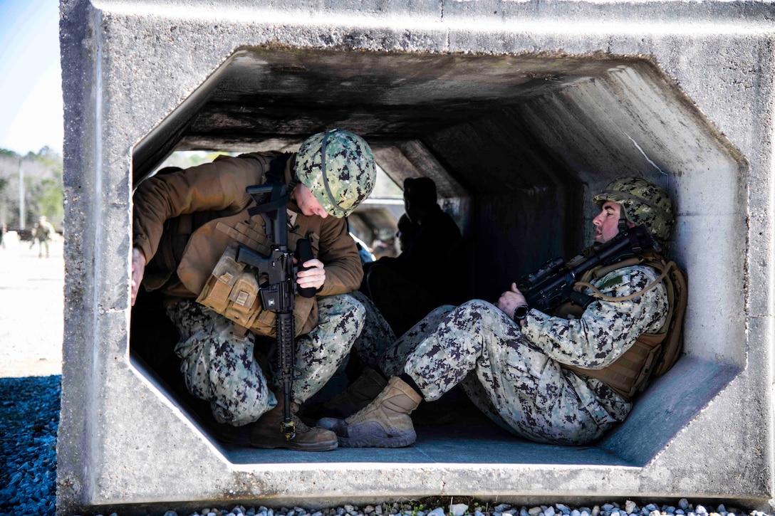 Sailors sit inside a shelter.