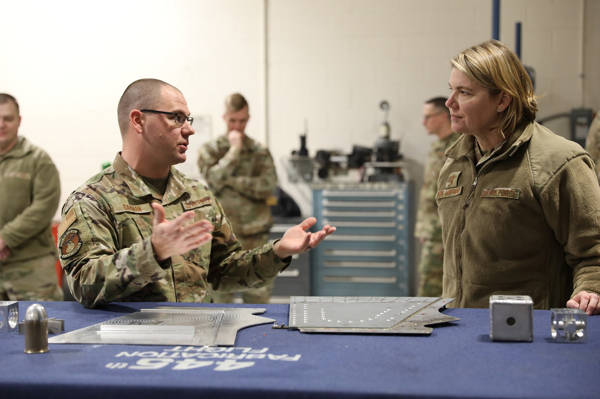 Senior Master Sgt. Nicholas Garman, 445th Maintenance Squadron fabrication flight
superintendent, shows Maj. Gen. C. McCauley von Hoffman, Director of Logistics, Civil Engineering, Force Protection and Nuclear Integration, Headquarters Air Force Materiel Command, two fabricated parts created by the metals technology shop during her tour of the shop, Jan. 8, 2023. Garman told her about the working relationship they have with Boeing engineers and how they support their manufacturing capabilities. He also highlighted the importance of funding the computer numerical control training, which is not taught in a technical school. While at the wing, the general received an overview briefing from both the 445th Mission Support Group and 445th Maintenance Group, she met with 21X officers during a senior leader perspective discussion, had lunch with both 445th MXG and MSG leadership and toured various maintenance facilities. Five Airmen, two from MSG and three from MXG, were coined by the general for being their group’s outstanding performer.