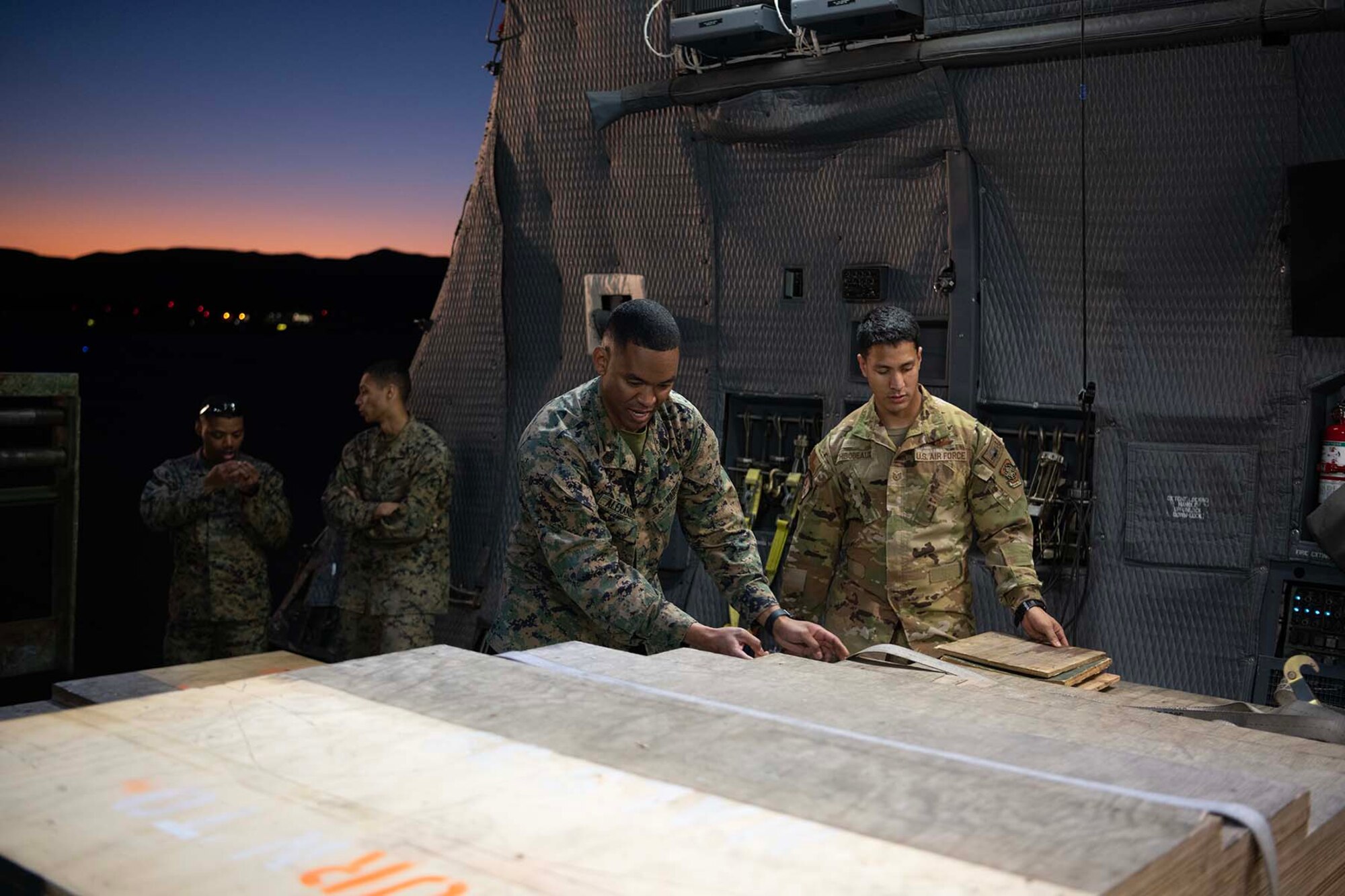 Maines and Airmen stand by cargo inside of an airplane