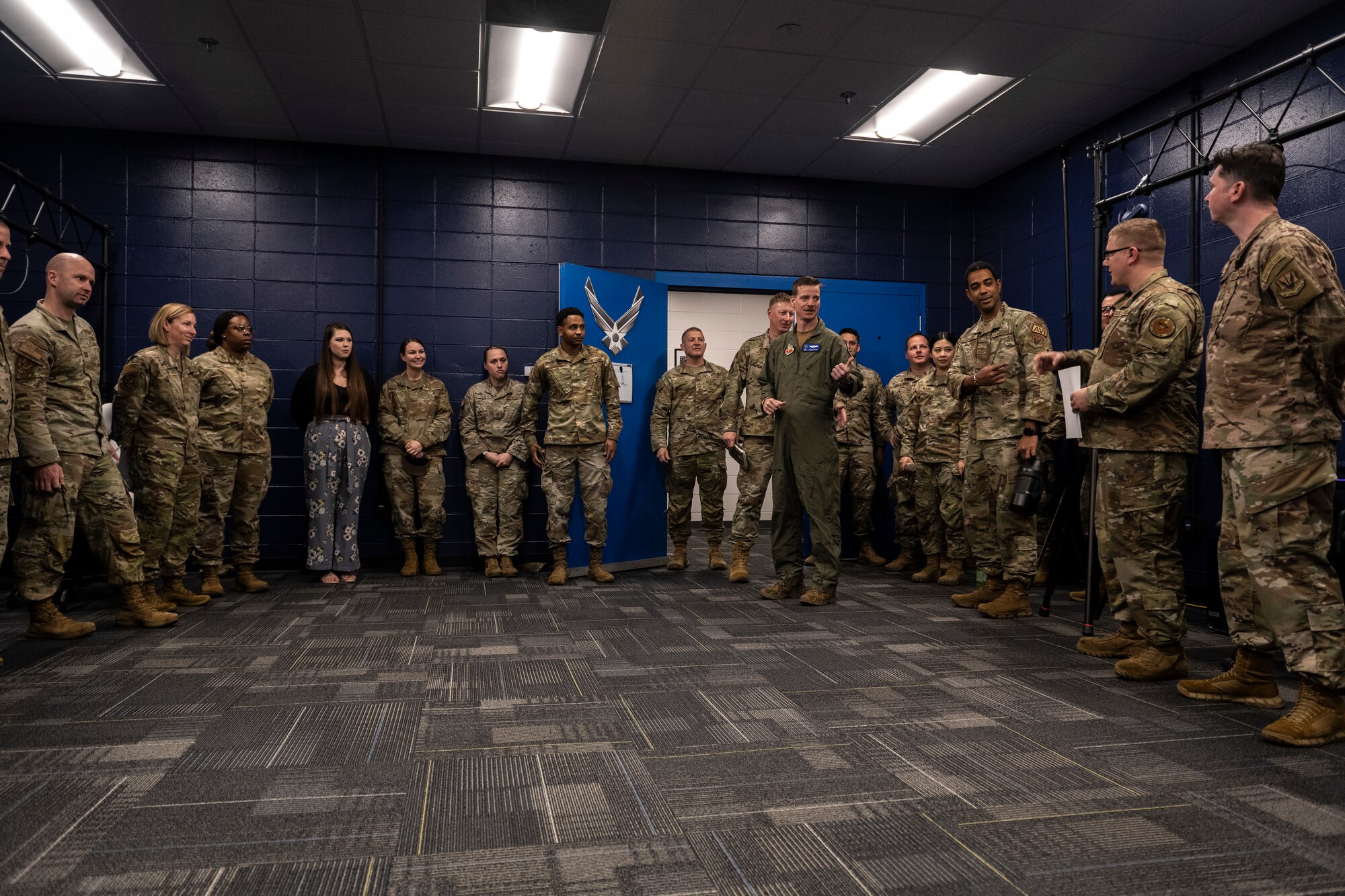 A photo of a bunch of Airmen standing in a room against the wall.