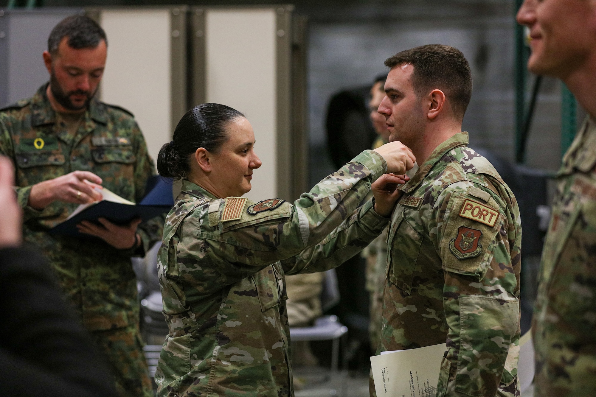 Lt. Col. Nicole Schatz, 88th Security Forces Squadron commander, pins a silver badge onto Tech. Sgt. Gabriel Clark, 87th Aerial Port Squadron ramp operations representative, after competing in the German Armed Forces Military Proficiency Badge qualification test at Wright-Patterson Air Force Base, Ohio, Feb. 3, 2023.