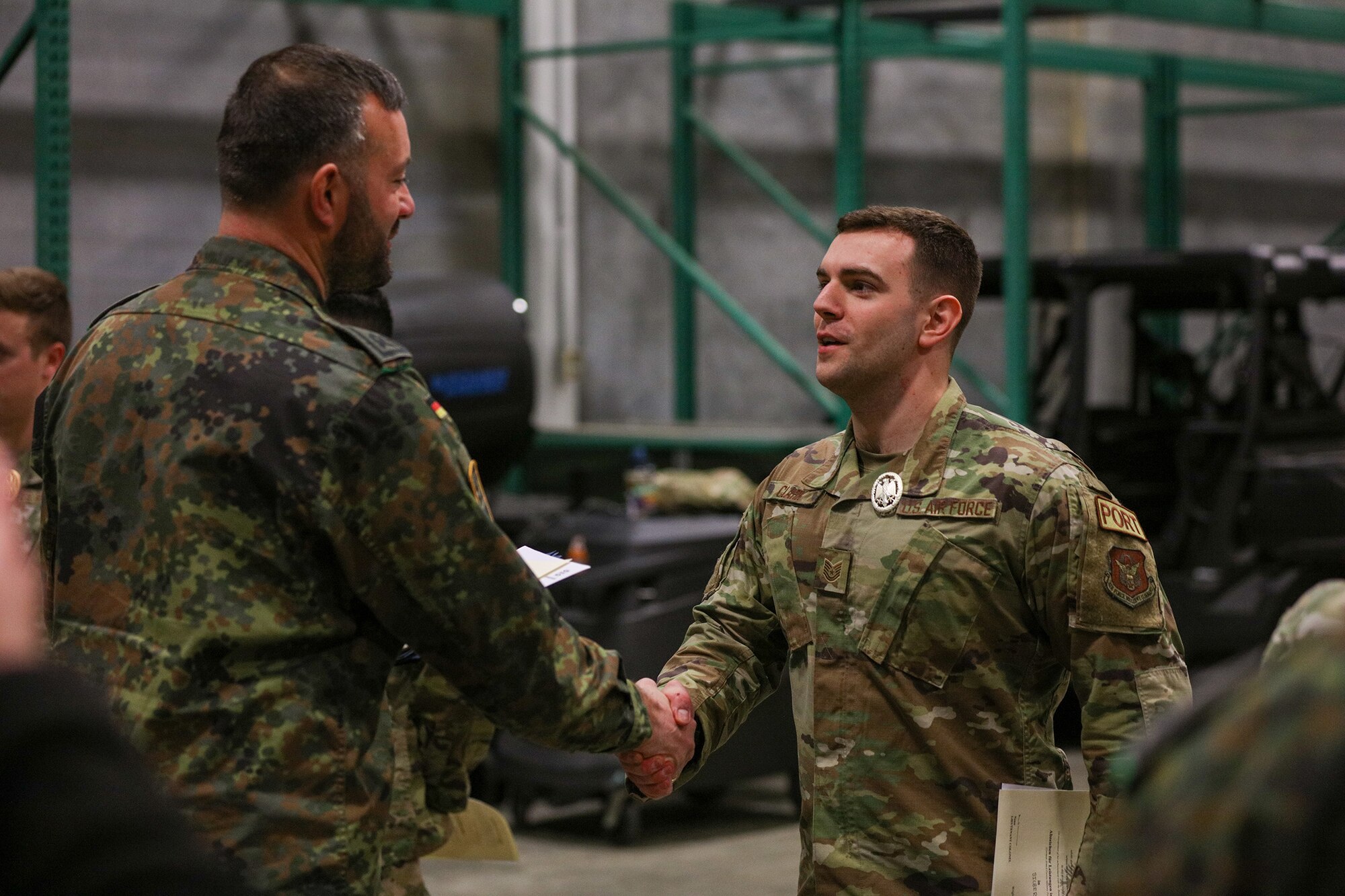 Master Sgt. Frederic Geiss, German Armed Forces team member, congratulates Tech. Sgt. Gabriel Clark, 87th Aerial Port Squadron ramp operations representative for competing and earning the silver badge in the German Armed Forces Military Proficiency Badge qualification at Wright-Patterson Air Force Base, Ohio, Feb. 3, 2023.