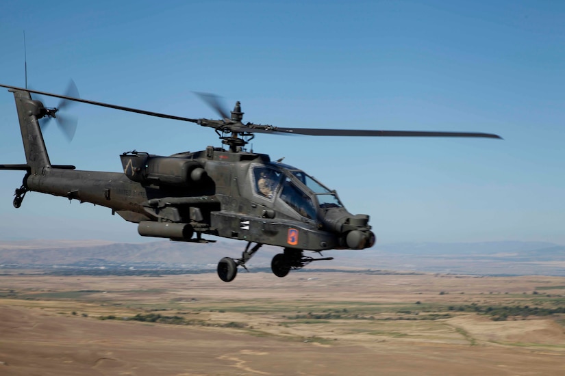 A helicopter flies over a landscape with hills in the background.