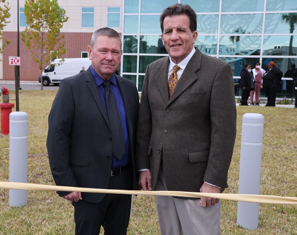 Two men standing at a ribbon cutting.