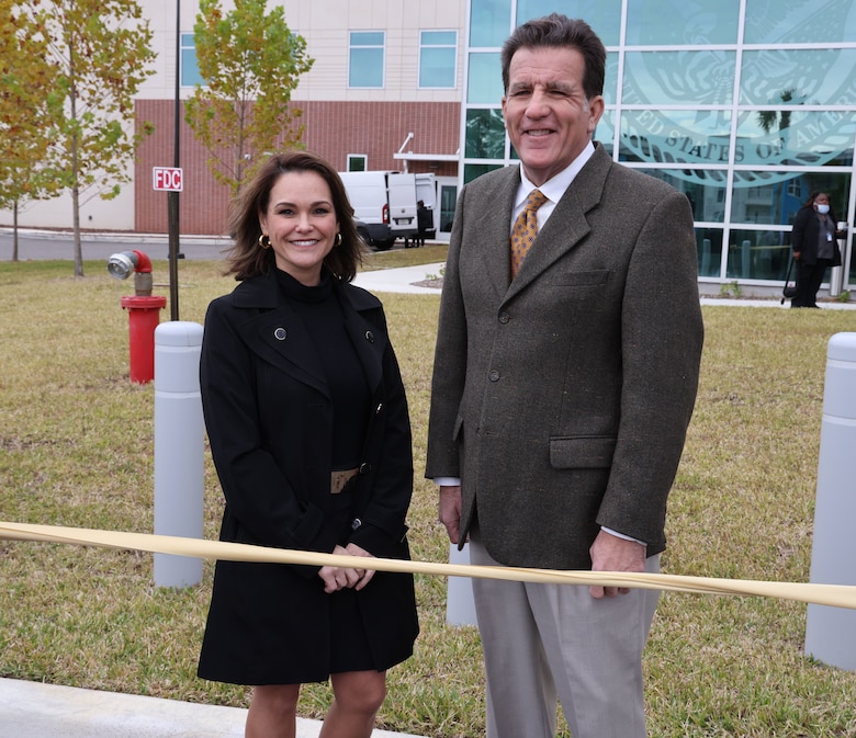 Man and woman standing at a ribbon cutting.