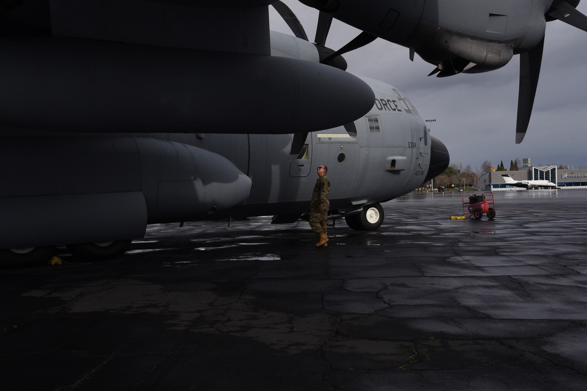 Male airman walks around aircraft conducting a visual inspection.