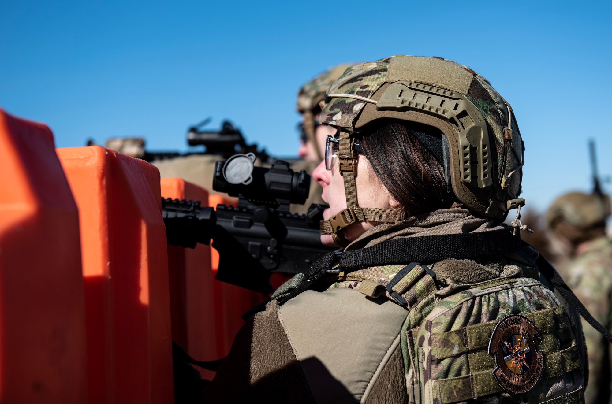 Senior Airman Billie Ayala, 22nd Security Forces Squadron patrolman, and other defenders hide behind a barricade during joint training at McConnell Air Force Base, Kansas, Feb. 3, 2023. Along with tactical approaches and retreats to clear buildings, the Airmen trained with U.S. Army Soldiers from the 3rd Assault Helicopter Battalion, 1st Aviation Regiment from Fort Riley, Kansas, to practice tactical takeoffs and landings in a UH-60 Blackhawk. (U.S. Air Force photo by Staff Sgt. Tryphena Mayhugh)