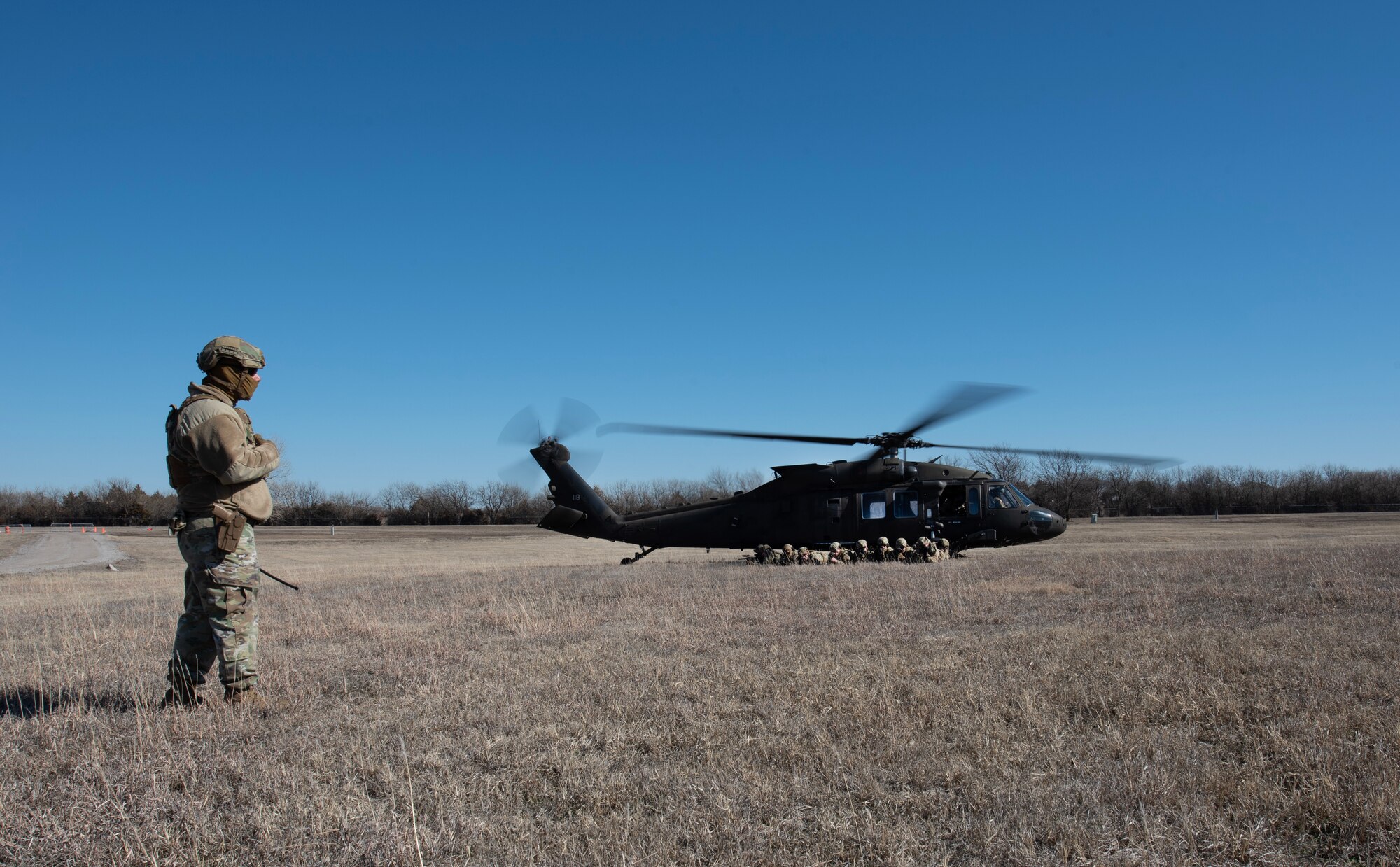 Master Sgt. Christopher Cervini, 22nd Security Forces Squadron chief of weapons and tactics, watches other 22nd SFS Airmen disembark a U.S. Army UH-60 Blackhawk during joint training at McConnell Air Force Base, Kansas, Feb. 3, 2023. The Airmen trained with U.S. Army Soldiers from the 3rd Assault Helicopter Battalion, 1st Aviation Regiment from Fort Riley, Kansas, to practice tactical takeoffs and landings in the Blackhawk. (U.S. Air Force photo by Staff Sgt. Tryphena Mayhugh)