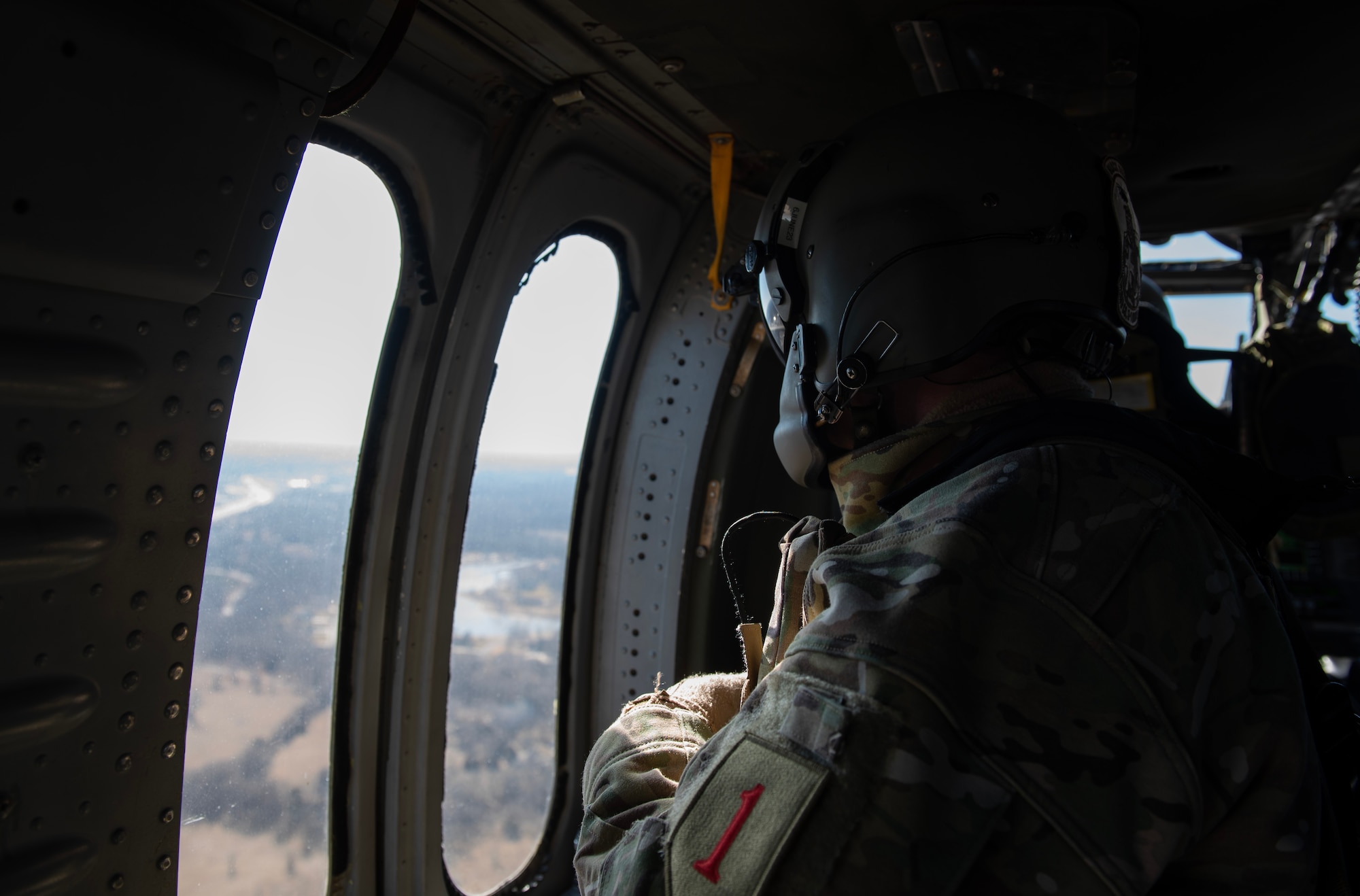 A U.S. Army Soldier from the 3rd Assault Helicopter Battalion, 1st Aviation Regiment at Fort Riley, Kansas, looks out of a UH-60 Blackhawk during a joint training flight over McConnell Air Force Base, Kansas, Feb. 3, 2023. Airmen from the 22nd Security Forces Squadron trained with the Soldiers to practice tactical takeoffs and landings in the Blackhawk during the training. (U.S. Air Force photo by Staff Sgt. Tryphena Mayhugh)