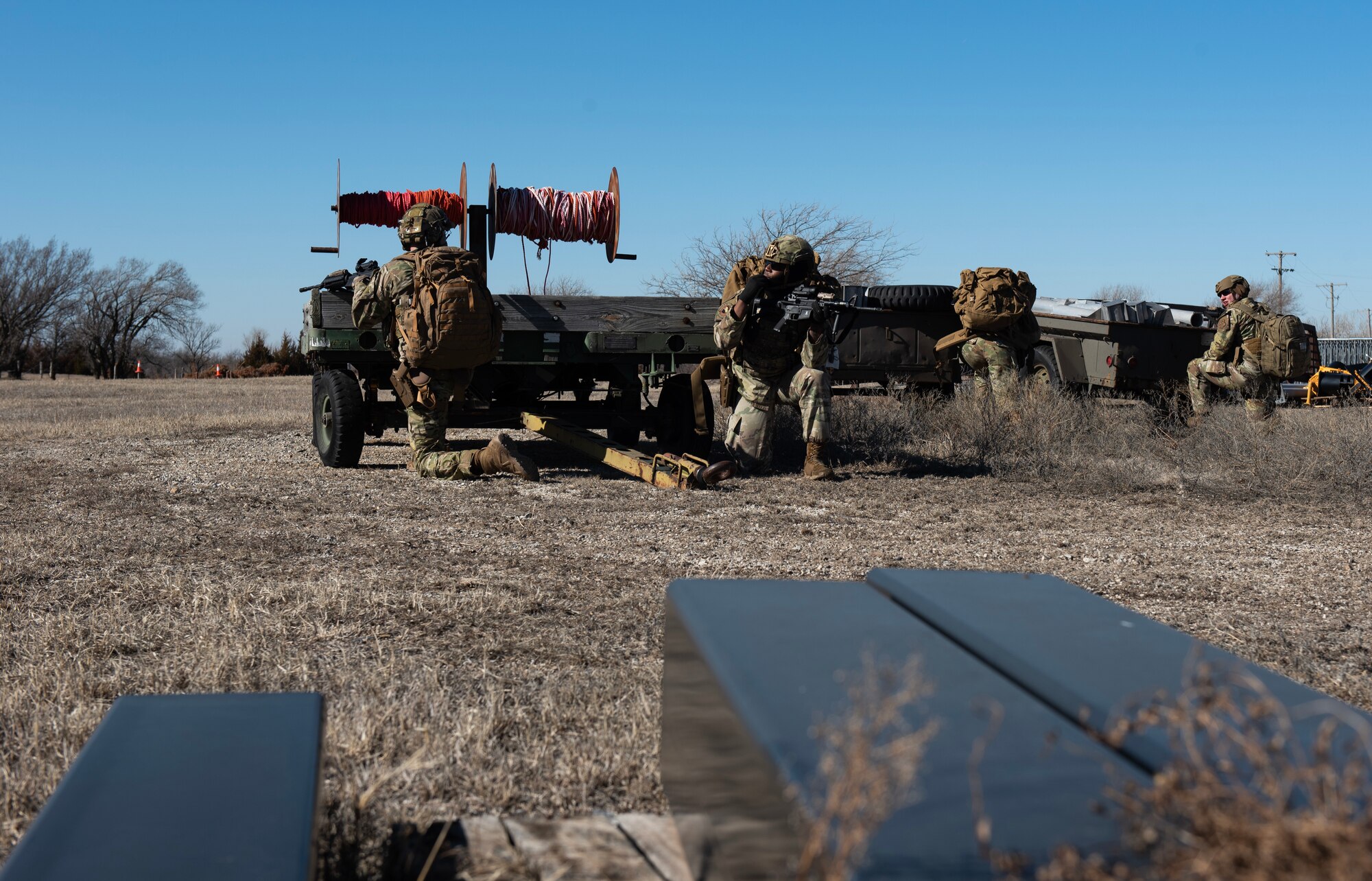 Airmen from the 22nd Security Forces Squadron hide behind cover during joint training at McConnell Air Force Base, Kansas, Feb. 3, 2023. Along with tactical approaches and retreats to clear buildings, the Airmen trained with the U.S. Army Soldiers from the 3rd Assault Helicopter Battalion, 1st Aviation Regiment from Fort Riley, Kansas, to practice tactical takeoffs and landings in a UH-60 Blackhawk. (U.S. Air Force photo by Staff Sgt. Tryphena Mayhugh)