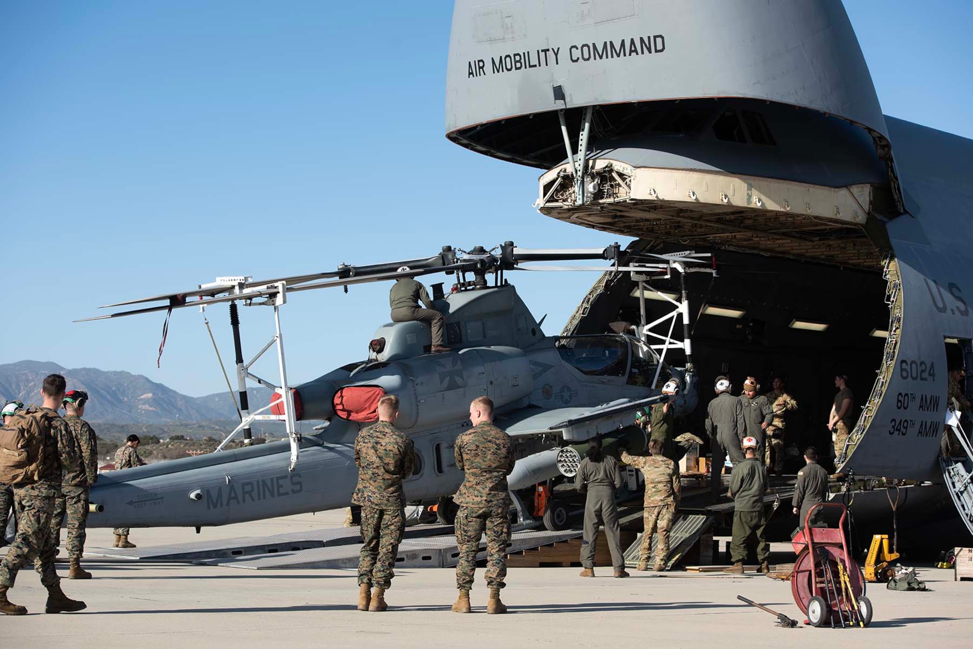 Marines and Airmen load a helicopter into a big airplane