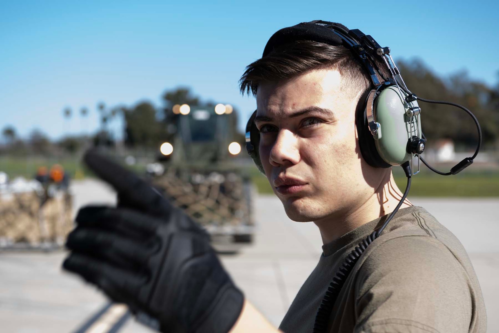 Airman points with his finger with cargo in the background