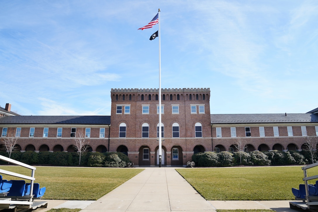 A brick-built Marine Corps barracks with a large, grass parade ground laid in front of it.