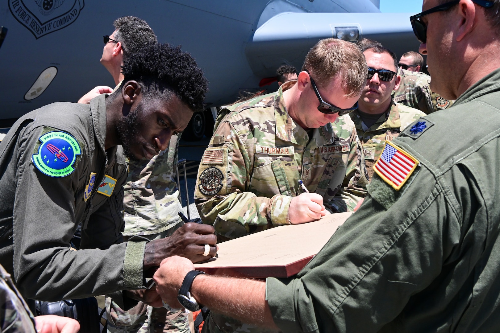U.S. Air Force Senior Airman Jenson Kokou, left, a boom operator assigned to the 92nd Air Refueling Wing, Fairchild AFB, Washington, and U.S. Air Force Staff Sgt. Nicholas Thurman, a maintainer assigned to the 92nd Aircraft Maintenance Squadron, sign their names on the back of a lithograph in Perth, Australia, Jan. 27, 2023. During each stop of Operation Vespucci, local community members were presented with lithographs to recognize and enhance partnerships with numerous countries in the Southern Hemisphere. (U.S. Air Force photo by 2nd Lt. Kristin Nielsen)