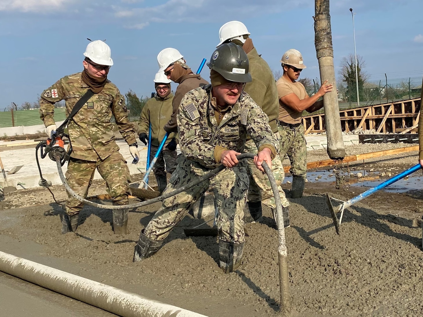221215-N-N0748-1083 POTI, Georgia (Dec. 15, 2022) Builder 2nd Class Ian Potter, assigned to Naval Mobile Construction Battalion (NMCB) 11, works with a soldier assigned to the Georgian Land Force’s 2nd Brigade Engineering Company to vibrate and strengthen the concrete pad for the Railhead Project in Poti, Georgia, Dec. 15, 2022. NMCB 11 operates as a part of Navy Expeditionary Combat Command and is assigned to Commander, Task Force 68 for deployment across the U.S. Naval Forces Europe-Africa area of operations to defend U.S., allied, and partner interests. (U.S. Navy photo by Builder Constructionman Gabriella Coupe)