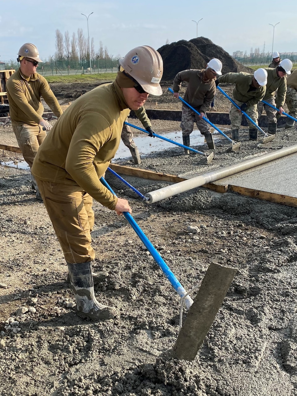 221215-N-N0748-1084 POTI, Georgia (Dec. 15, 2022) Steelworker 3rd Class Rusty Garza, assigned to Naval Mobile Construction Battalion (NMCB) 11, rakes concrete for the Railhead Project in Poti, Georgia, Dec. 15, 2022. NMCB 11 operates as a part of Navy Expeditionary Combat Command and is assigned to Commander, Task Force 68 for deployment across the U.S. Naval Forces Europe-Africa area of operations to defend U.S., allied, and partner interests. (U.S. Navy photo by Builder Constructionman Gabriella Coupe)