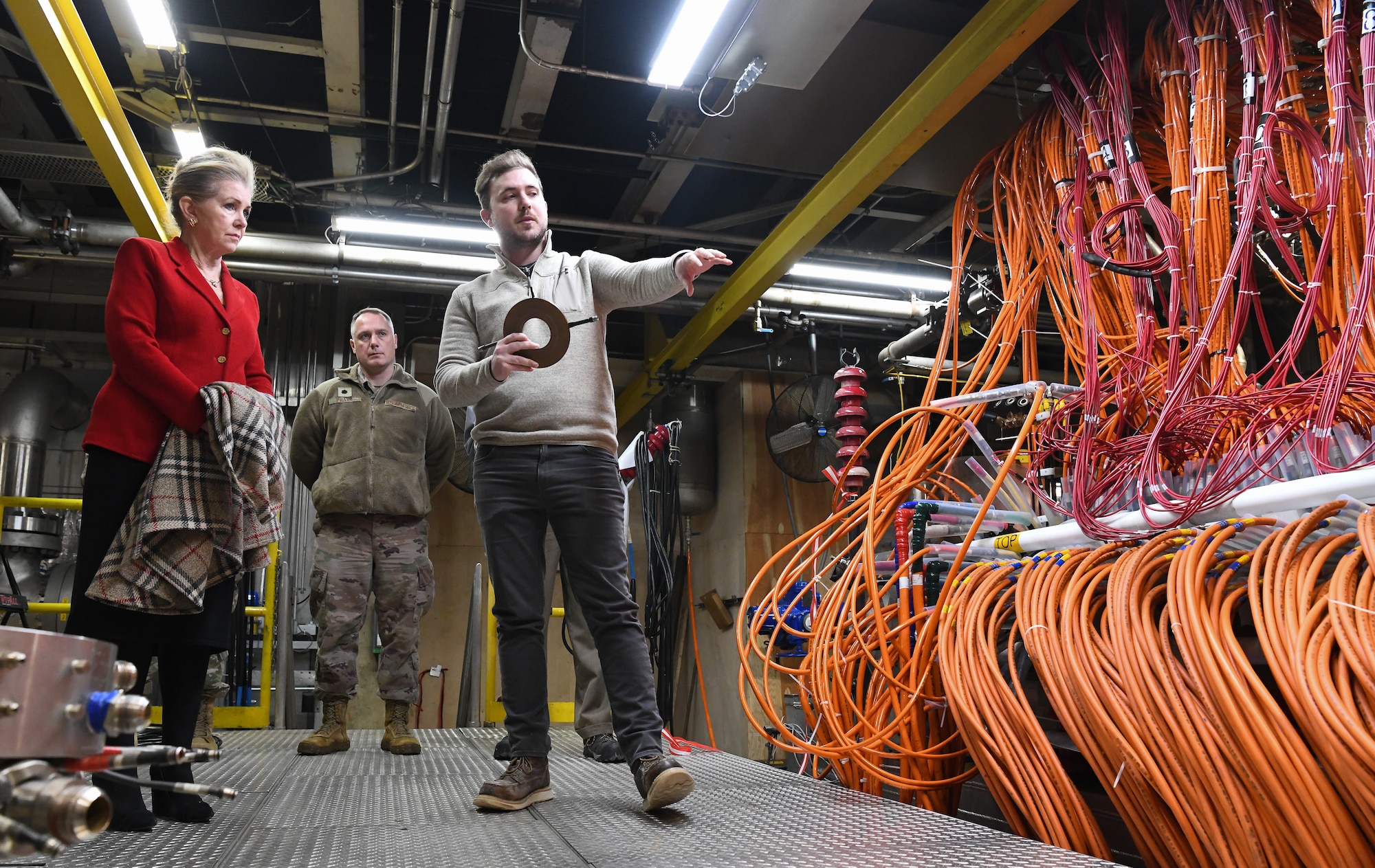 Man pointing to test equipment as woman and another man listen