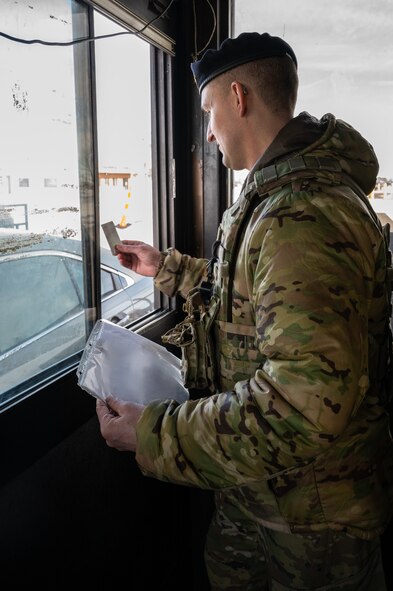 U.S. Air Force Staff Sgt. Nicholas Thompson, 5th Security Forces Squadron response team leader, checks the identification of personnel coming through a security checkpoint at Minot Air Force Base, North Dakota, Feb. 2, 2023. Entry controllers ensure the safety of the people, property and resources on every Air Force base. (U.S. Air Force photo by Airman 1st Class Alexander Nottingham)