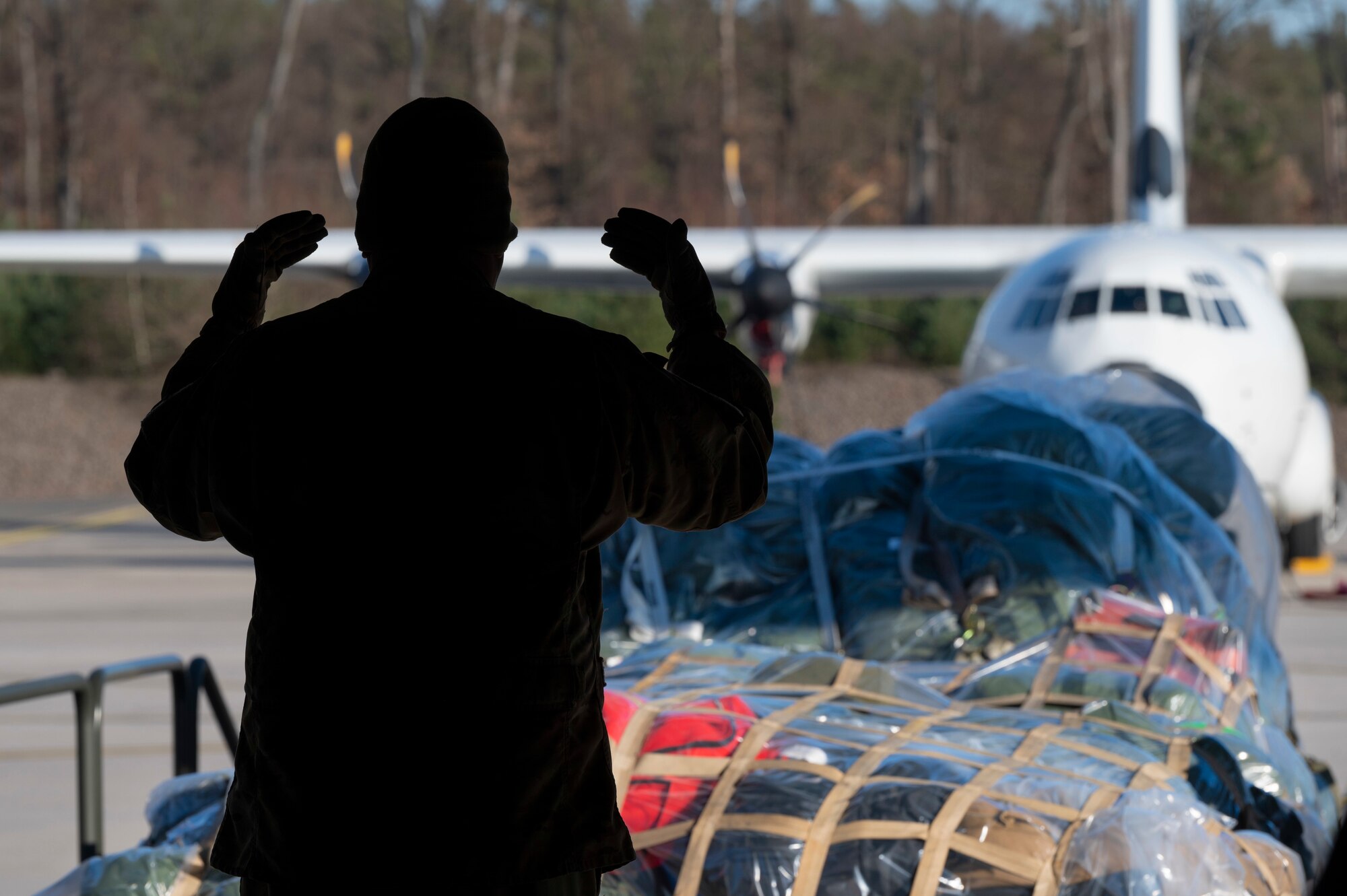 A loadmaster from the 37th Airlift Squadron guides palettes of luggage onto a C-130J Super Hercules aircraft at Ramstein Air Base, Germany, Feb. 8, 2023.