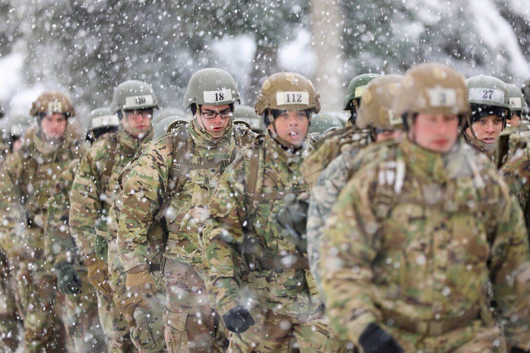 U.S., Greek and Dutch troops walk in formation in the snow.