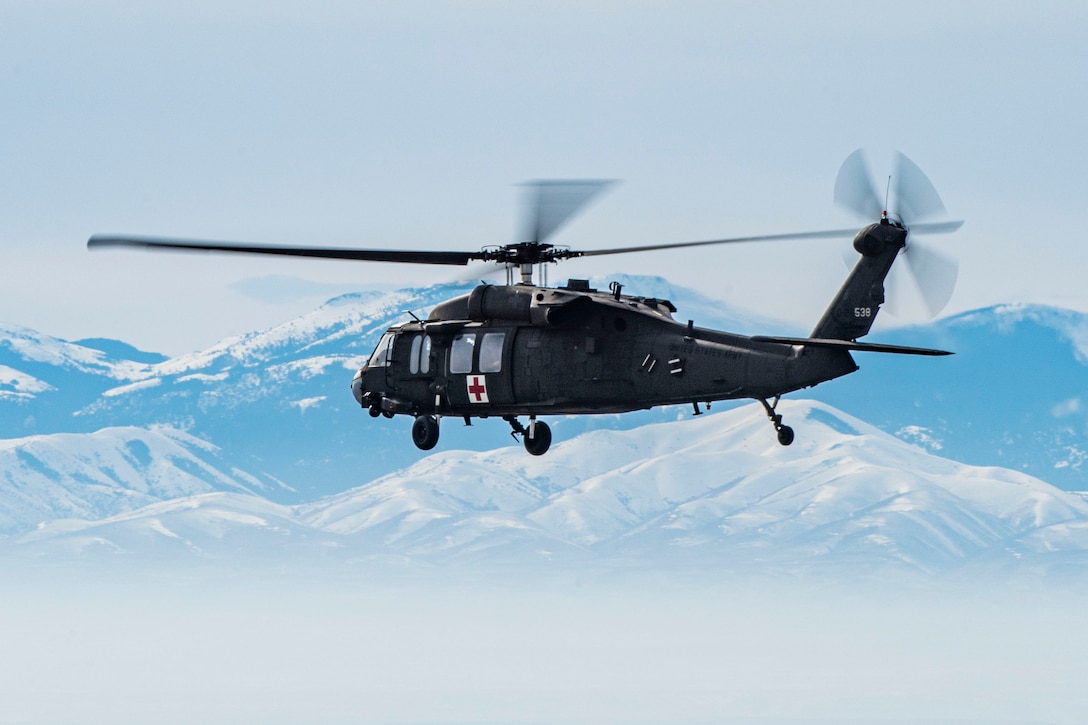 A helicopter flies in front of a mountain range.