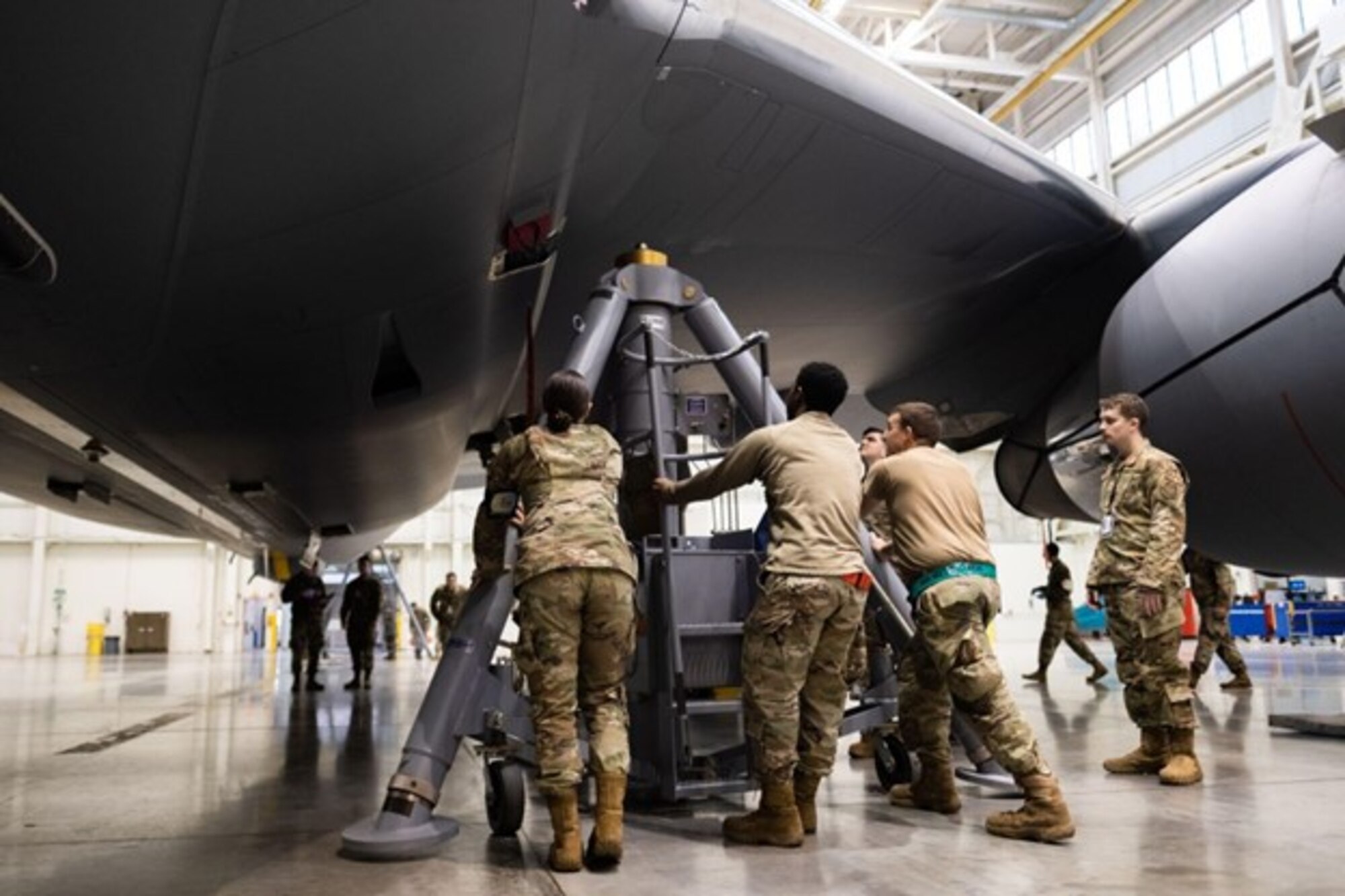 Group of maintainers push a large piece of equipment