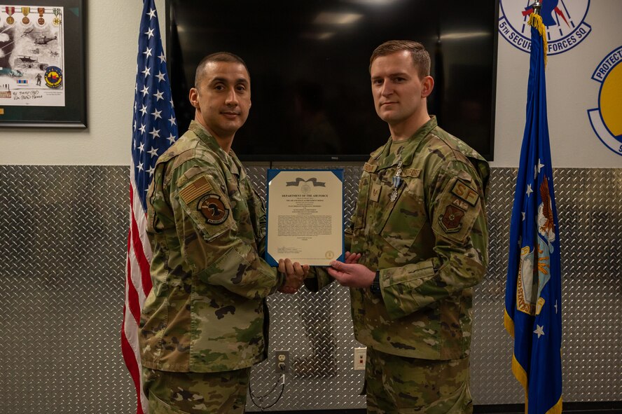 U.S. Air Force Staff Sgt. Nicholas Thompson, 5th Security Forces Squadron response team leader (right), is awarded the Air And Space Achievement Medal at Minot Air Force Base, North Dakota, Feb. 10, 2023. Thompson was awarded the medal for taking heroic action that saved a fellow Airman's life. (U.S. Air Force Photo by Airman 1st Class Alexander Nottingham)