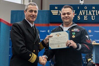 Rear Adm. Pete Garvin, commander, Naval Education and Training Command (NETC), presents a Navy and Marine Corps Commendation Medal to Electronics Technician 2nd Class Sean Poulson, assigned to Surface Combat Systems Training Command, San Diego, for his selection as the junior enlisted military instructor of the year during the Military Instructor of the Year 2022 awards ceremony at the National Naval Aviation Museum onboard Naval Air Station Pensacola, February 10, 2023. NETC’s mission is to recruit, train and deliver those who serve our nation, taking them from street-to-fleet by transforming civilians into highly skilled, operational and combat ready warfighters. (United States Navy photo by Mass Communication Specialist 2nd Class Zachary Melvin)