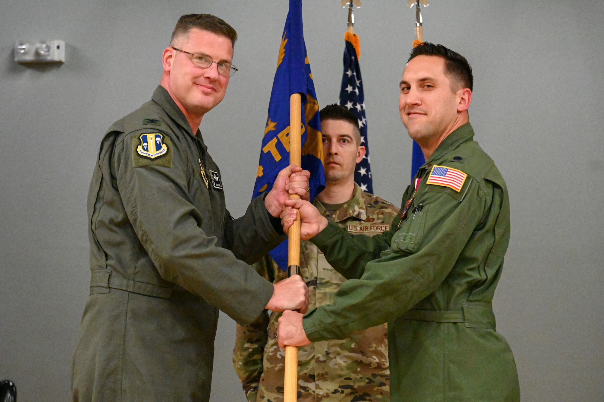 Men in uniform hold the guidon and pose for a photo.