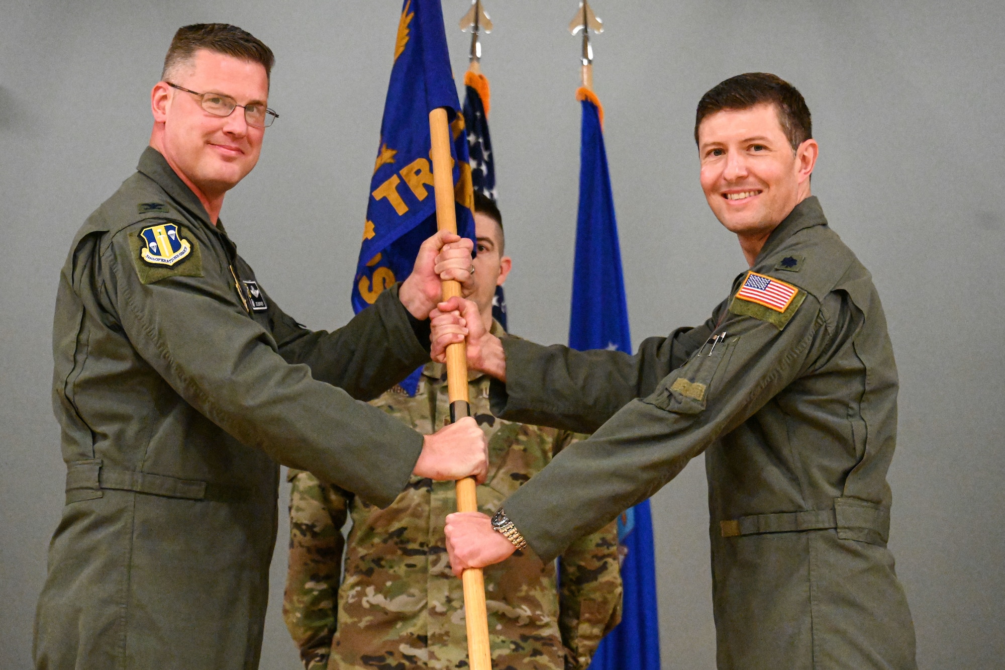Men in uniform hold the guidon for a photo.