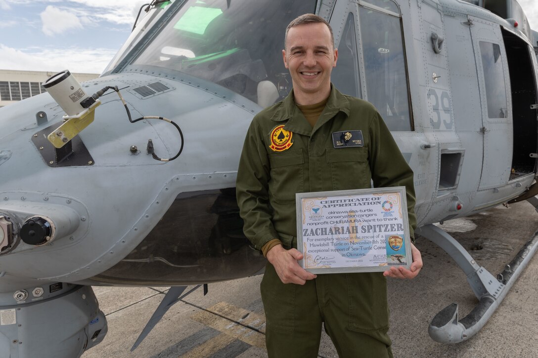 U.S. Marine Corps Master Sgt. Zachariah Spitzer, the avionics chief for Marine Light Attack Helicopter Squadron (HMLA) 267, poses for a photo in front of a UH-1Y Venom at Marine Corps Air Station (MCAS) Futenma, Jan. 9, 2023. Spitzer was presented a certificate for rescuing an endangered Hawksbill Sea Turtle. (U.S. Marine Corps photo by Lance Cpl. Emily Weiss)