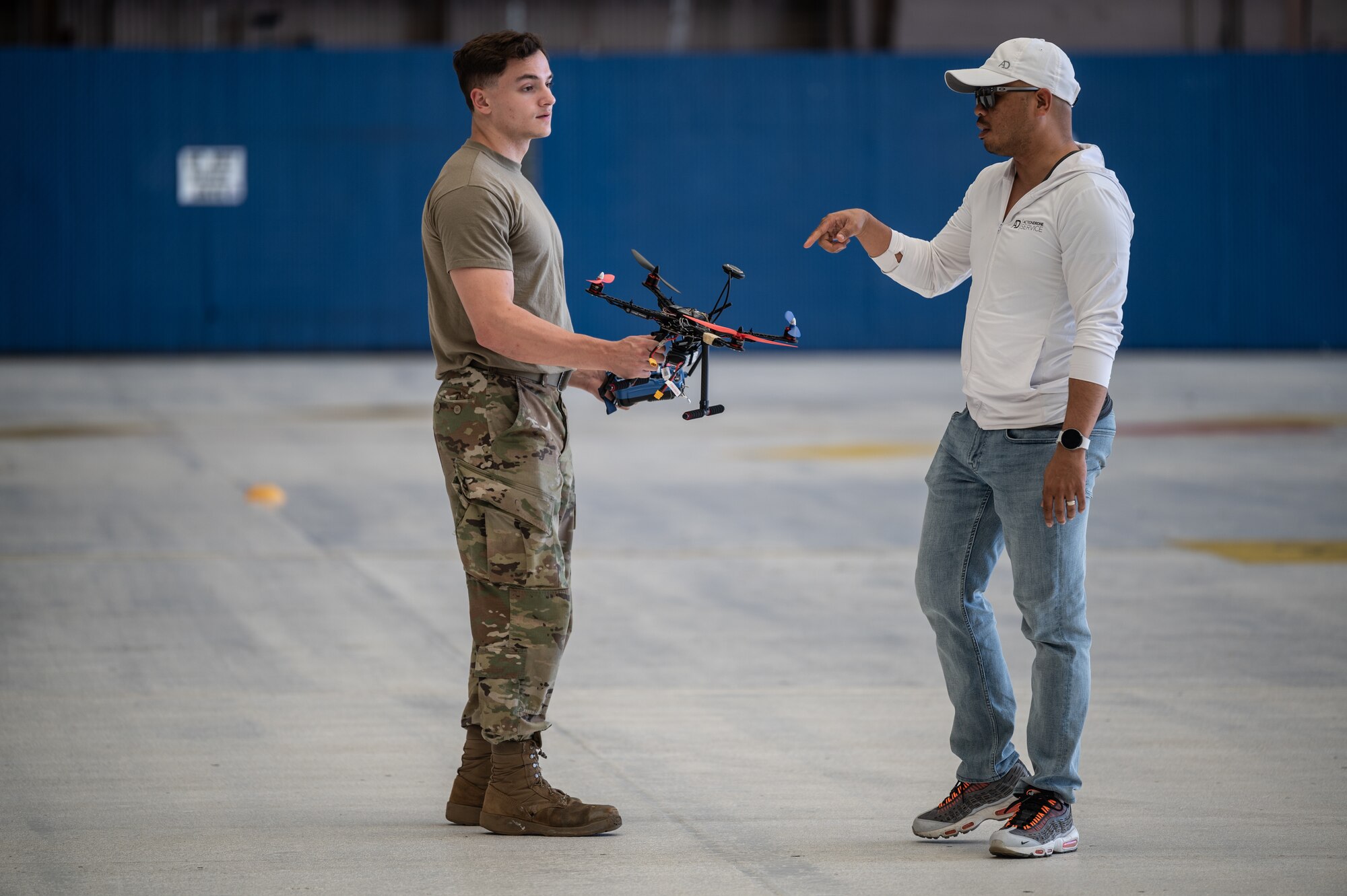 Airman 1st Class Colin Moore, 15th Maintenance Squadron aircraft structural maintenance journeyman, speaks with Darryl Anunciado, a contracted flight instructor, during drone flight training at Joint Base Pearl Harbor-Hickam, Hawaii, Feb. 8, 2023. Contracted personnel are utilizing a curriculum they created to train 15th MXS and 154th Maintenance Squadron airmen on basic flight movements with a trainer drone. (U.S. Air Force photo by Staff Sgt. Alan Ricker)